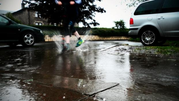 Person stepping in surface water with street in background - Photo credit: Julian Scott