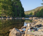 River with camping stove on stones in foreground. Photo credit: Rachel Helliwell