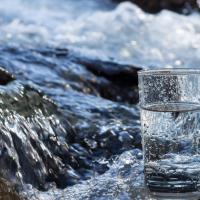 Glass of water with flowing stream in background. Sourced from istock. copyight restrictions apply