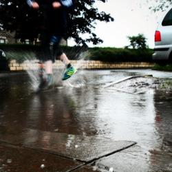 Person stepping in surface water with street in background - Photo credit: Julian Scott
